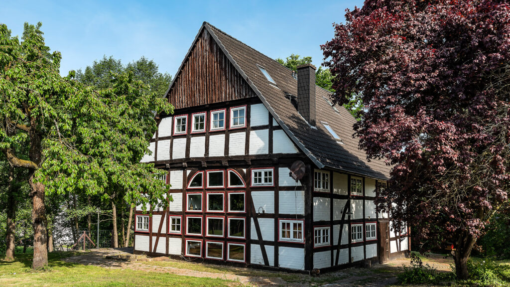 Denkmalschutz: Ein altes Denkmal (Fachwerkhaus), umgeben von Bäumen.
