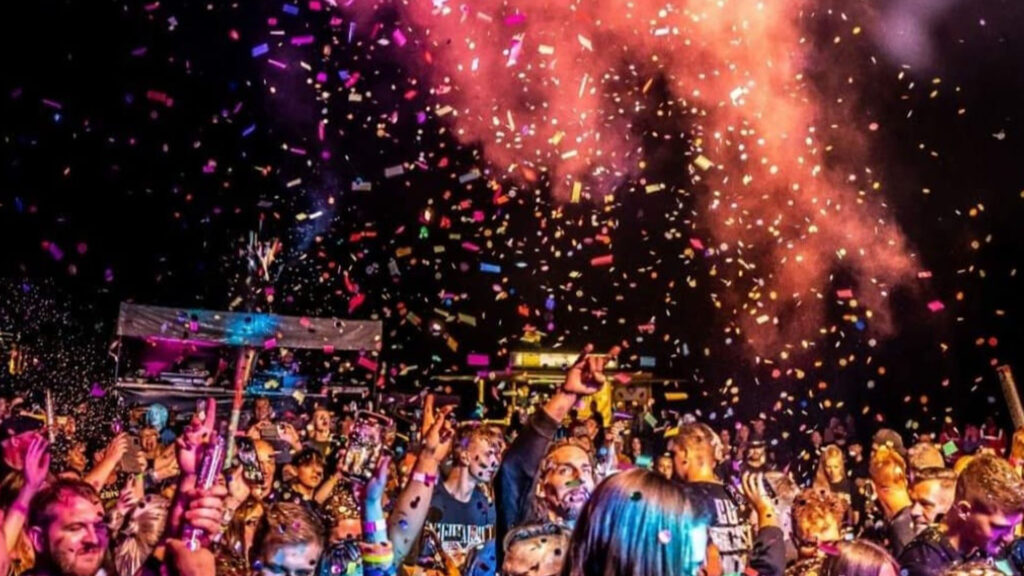 Partystimmung beim Rock am Köterberg. Dunkler Nachthimmel mit buntem Konfetti und feiernden Menschen.